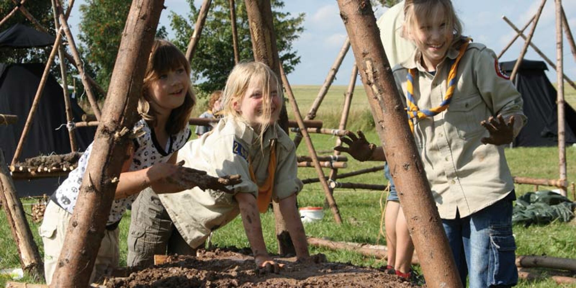 Kinder, die eine Feuerschale aus Lehm gebaut haben.